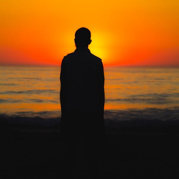 Silhouette of a man stretching against a vibrant sunrise.